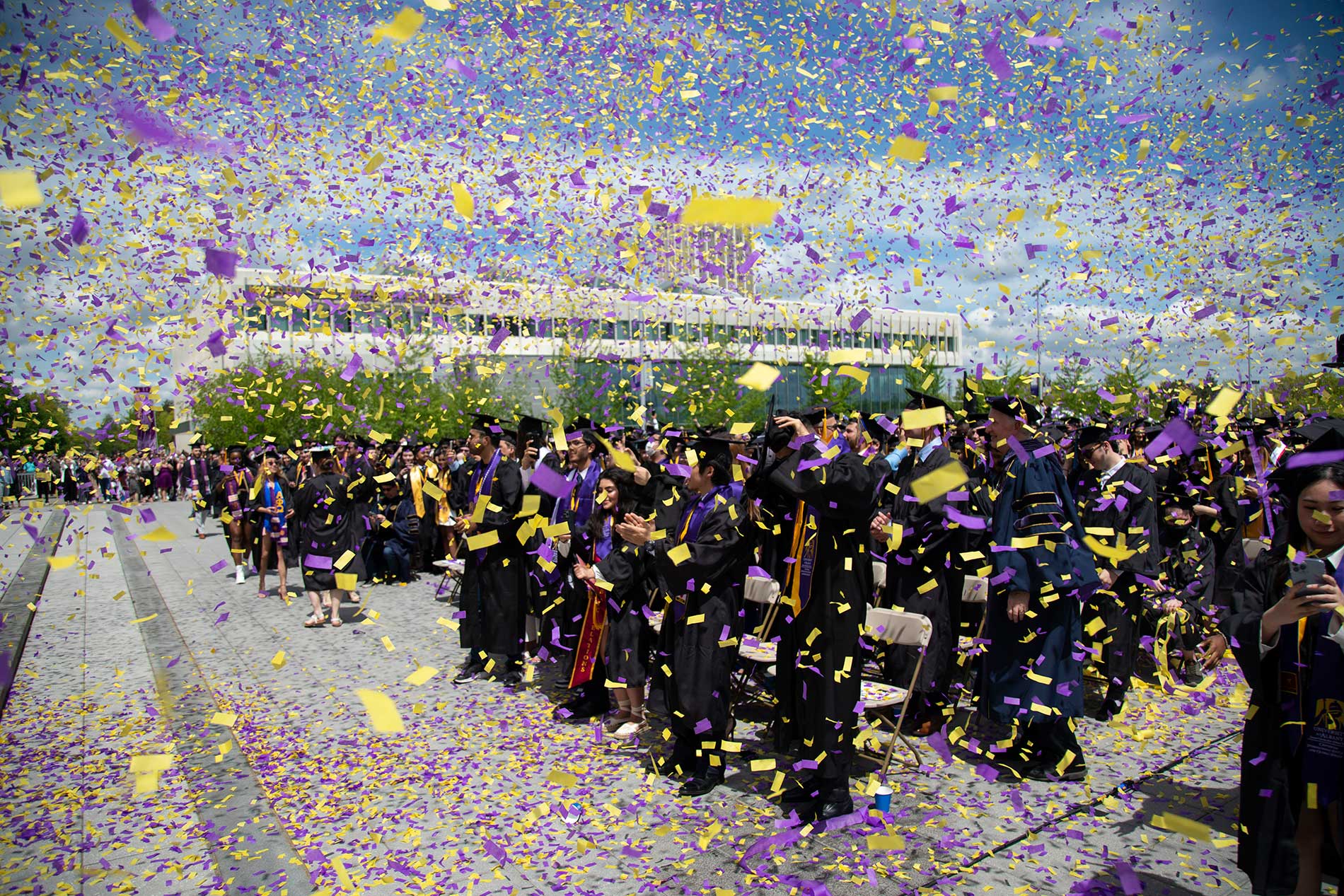 Students celebrating at commencement as confetti is released
