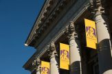 Yellow UAlbany banners hang from the ornate columns of Draper Hall
