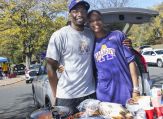 A couple stands in frount of their tailgating picnic.