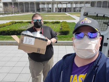Stephen Conard (right) hands off a box of donated face shields to Eric Gaunay, CEHC alum and emergency preparedness coordinator at the Rensselaer County Bureau of Public Safety.