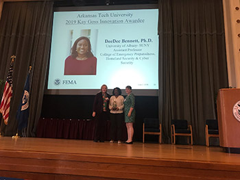 DeeDee Bennett accepts 2019 Kay Goss Technology and Innovation Award on stage at the Federal Emergency Management Agency (FEMA) Higher Ed Symposium.