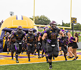 UAlbany Football runs out from inflatable helmet.