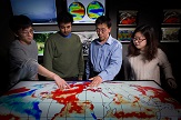 Liming Zhou and students point to a map which displays their research about sea surface temperature variability and its effects on drought in the Congo.