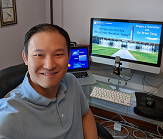 Brian Tang sits in front of computer before virtually speaking with classroom of students.