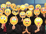 People holding emoji masks.
