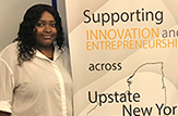 Start-up entrepreneur Fatouma Diallo '18 stands before an Ignite NY poster