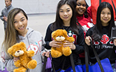 Female students hold up Teddy bears in support of We Care