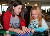 A CNSE staff member helps a visitor at CNSE Community Day