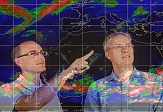 Professors Ryan Torn and Christopher Thorncroft study a weather map