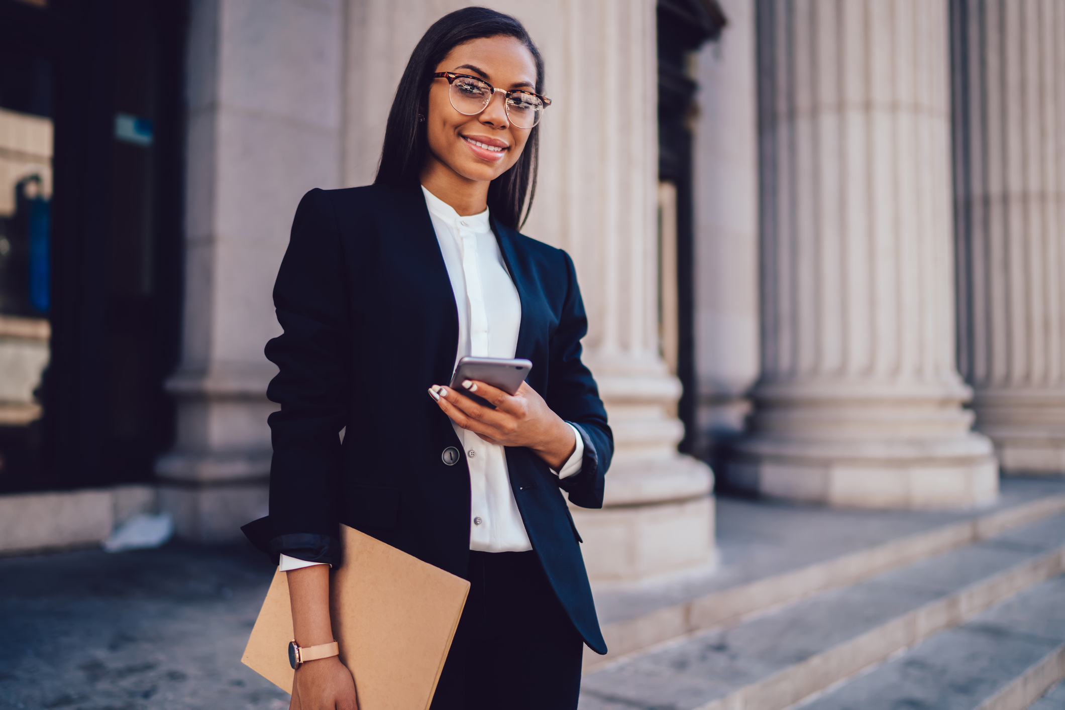 Young professional woman holding a folder and using a smartphone
