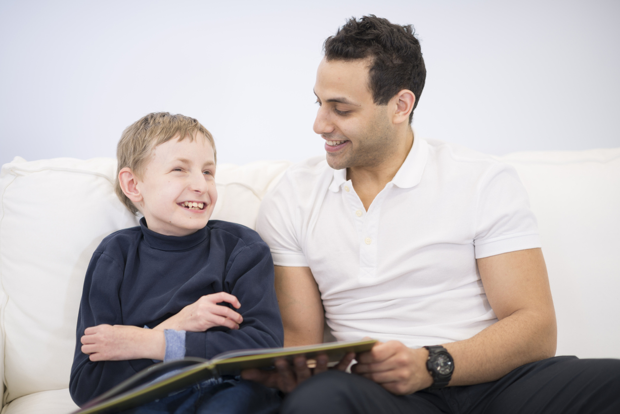 A man reads a book with an autistic child