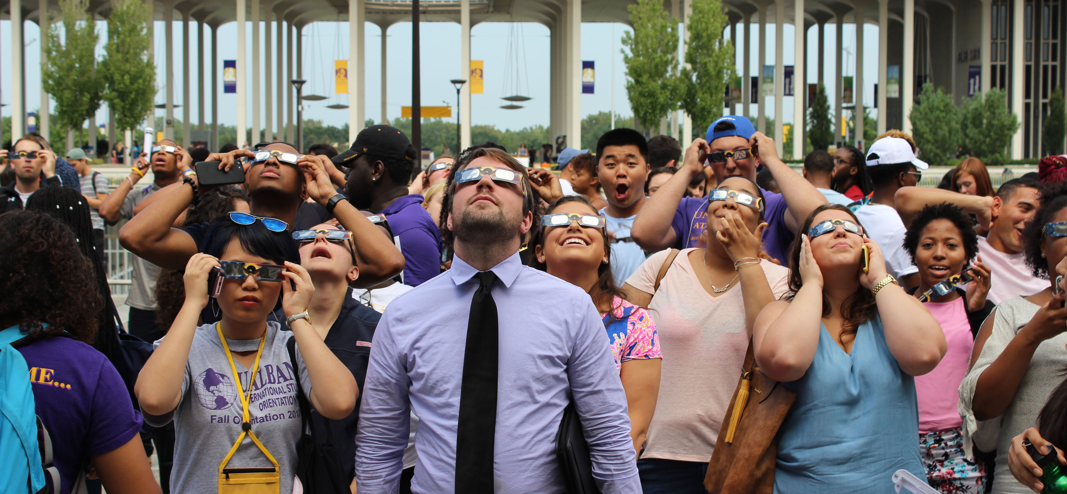 A crowd of people wearing eclipse glasses looks up at the sky ahead of the 2017 solar eclipse.