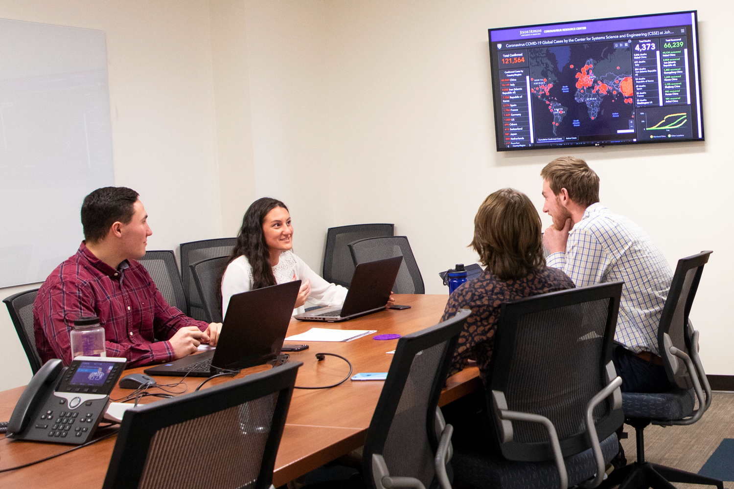 A group of four UAlbany students working in the Virtual Operations Support Team lab.
