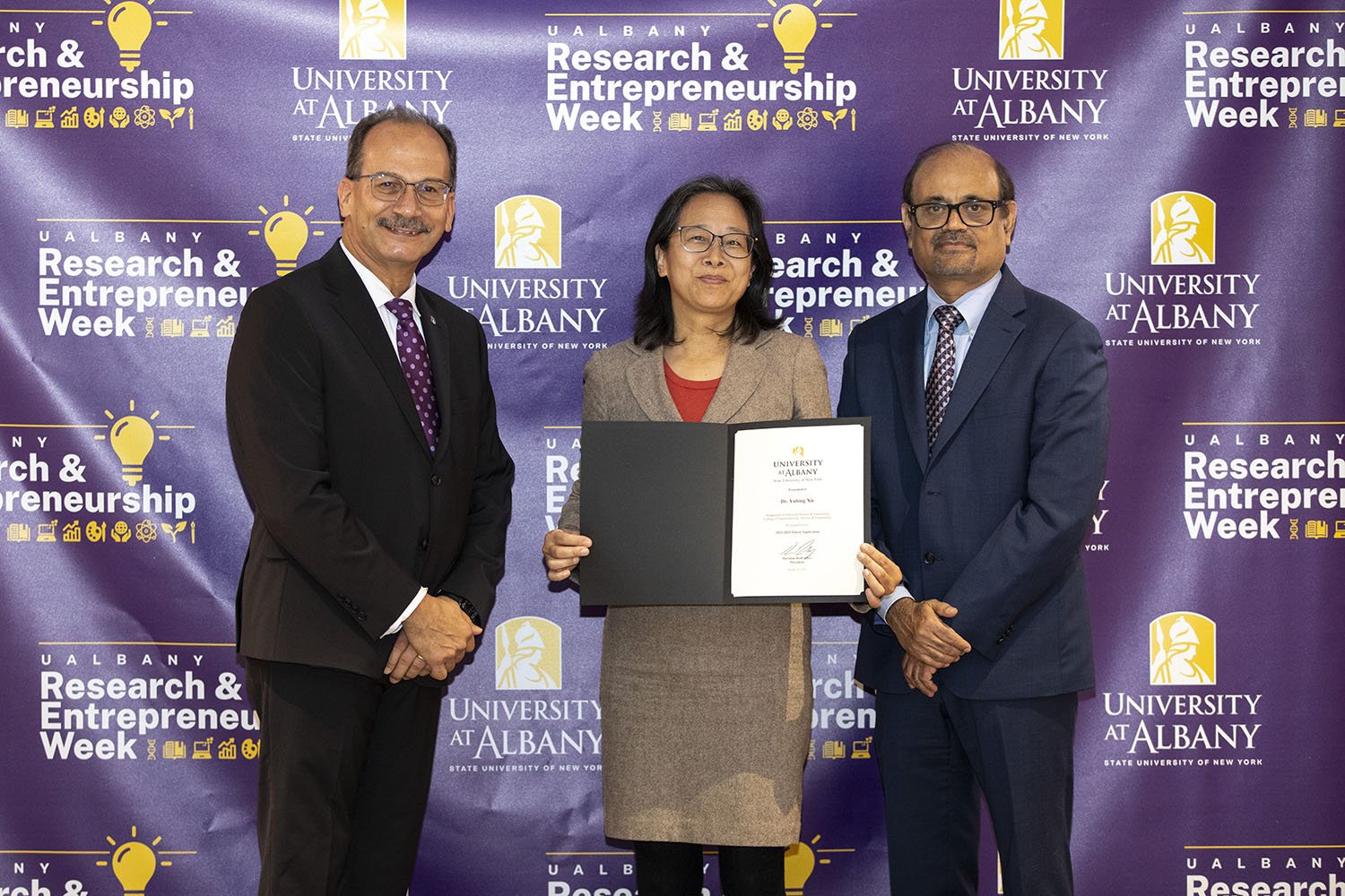 Yubing Xie, CNSE, with UAlbany President Havidán Rodríguez and Vice President for Research and Economic Development Thenkurussi “Kesh” Kesavadas.