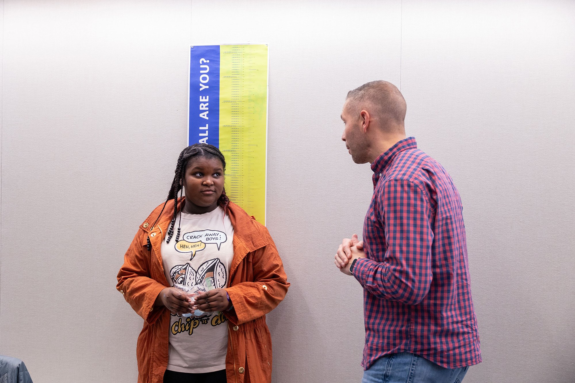 A scientist speaks to a young girl standing in front of a sign detailing height at UAlbany's STEM & Nanotechnology Family Day at ETEC.