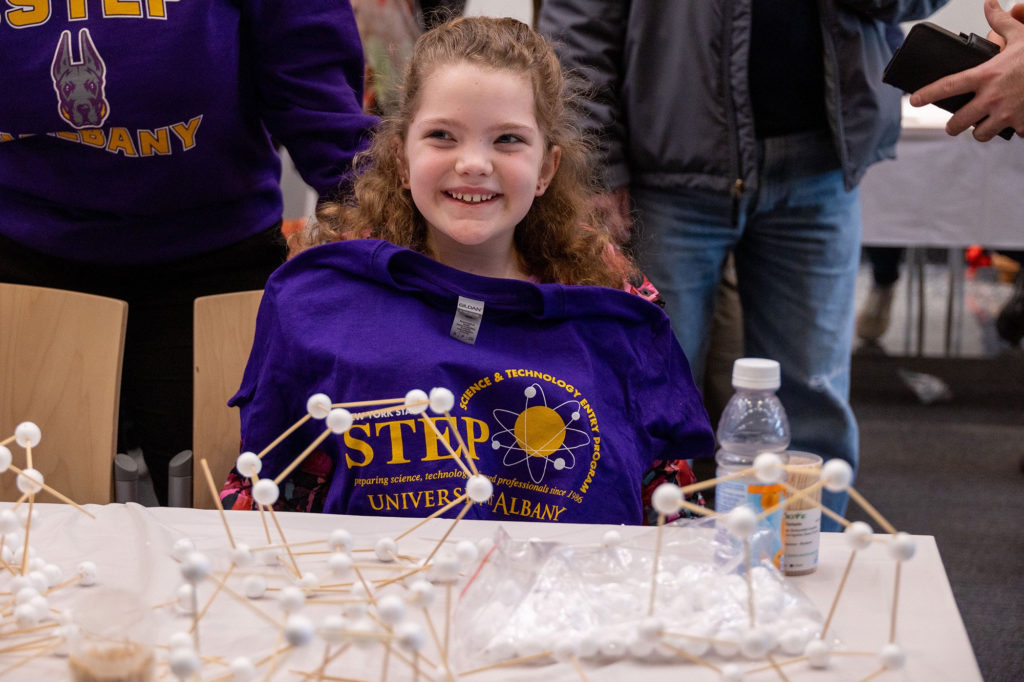 A young girl smiles with her new t-shirt at UAlbany's STEM & Nanotechnology Family Day at ETEC.