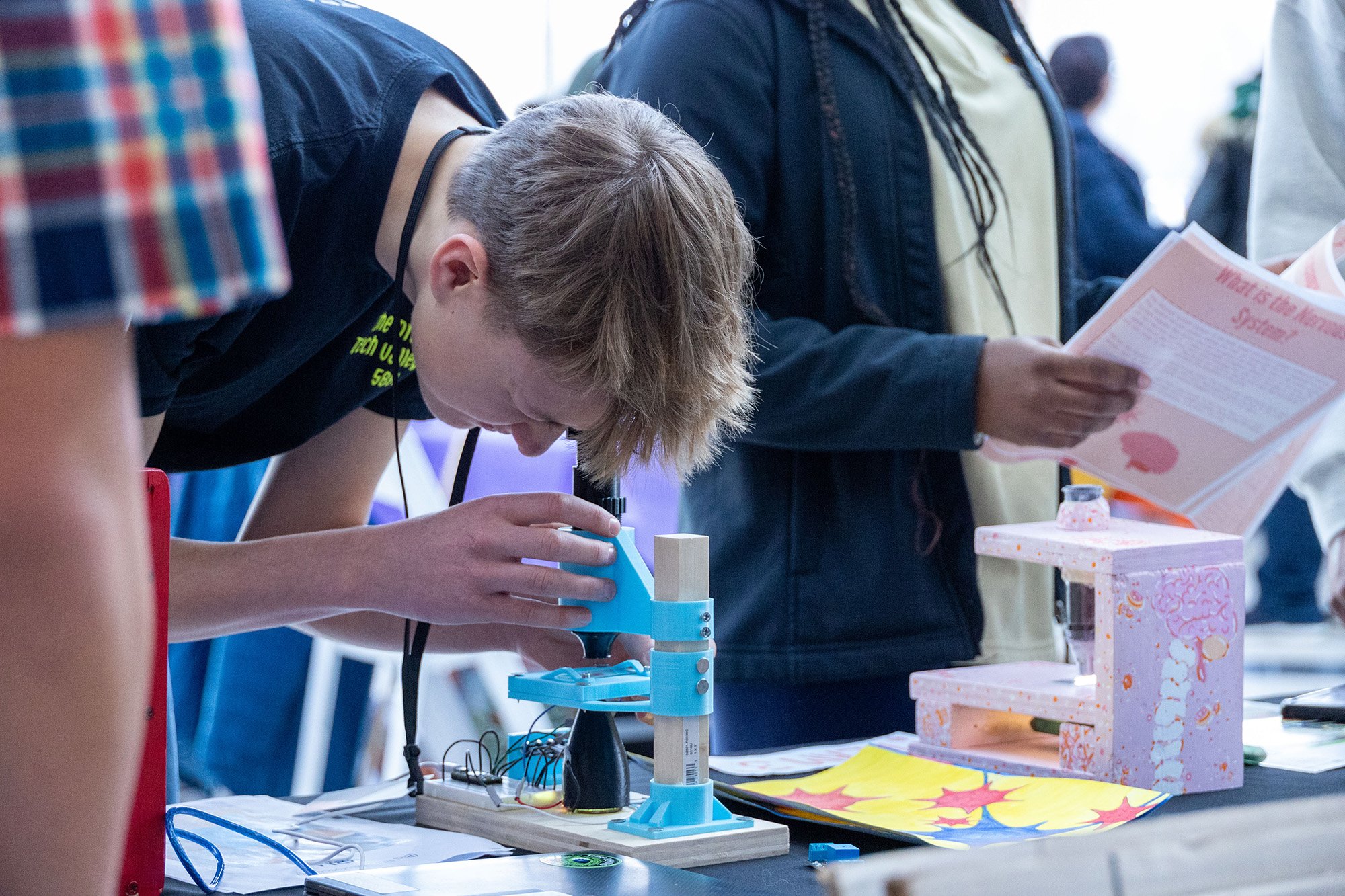 A young man looks through a microscope on a table at UAlbany's STEM & Nanotechnology Family Day at NY CREATES' Albany NanoTech Complex.