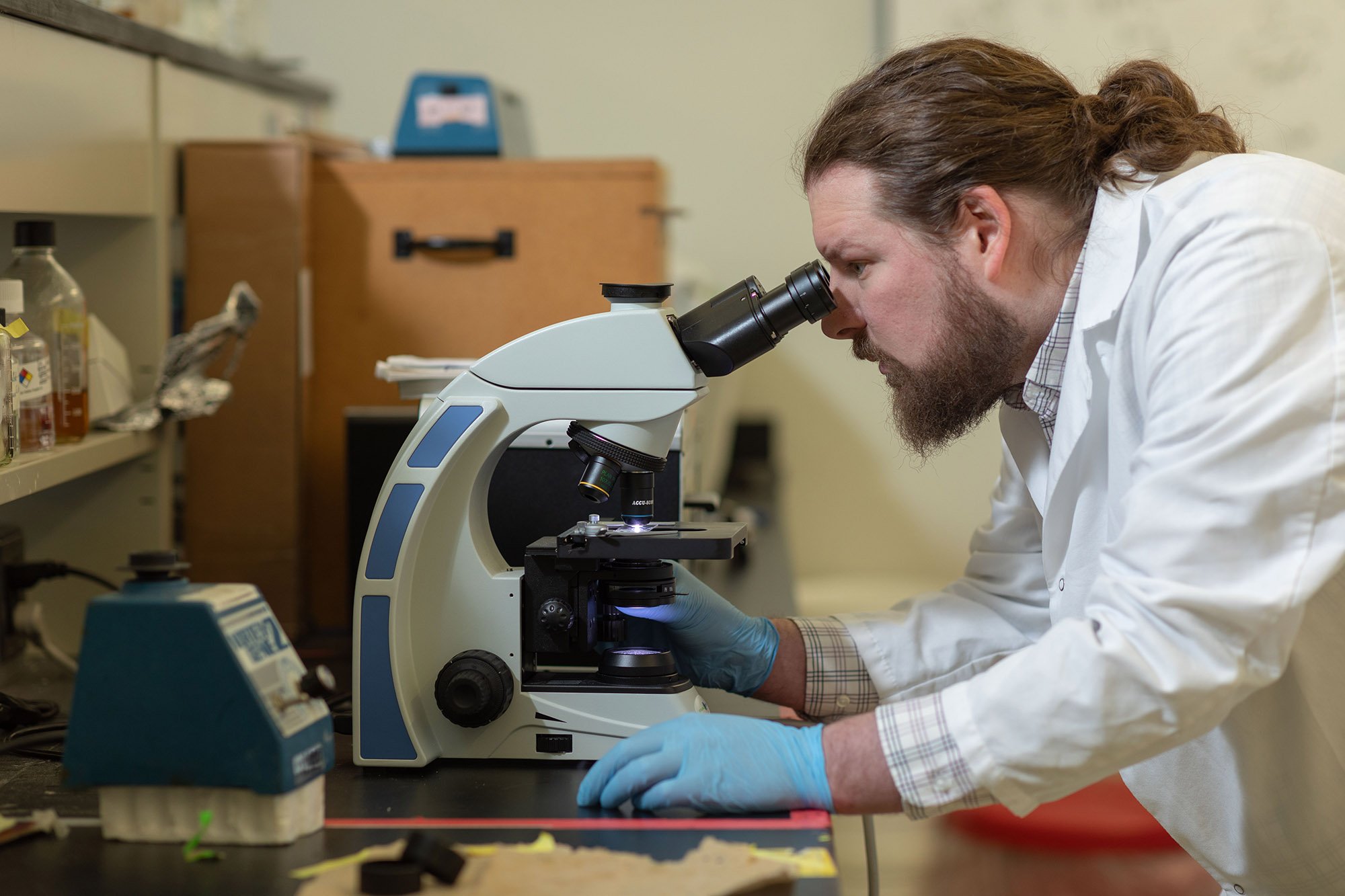 PhD student Michael Dolan looks into a microscope in the lab of Mike Fasullo