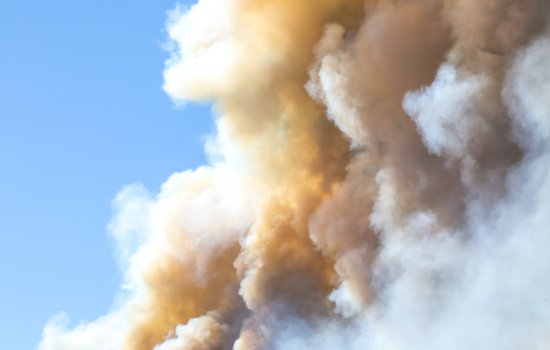 White and brown smoke covers a blue sky.