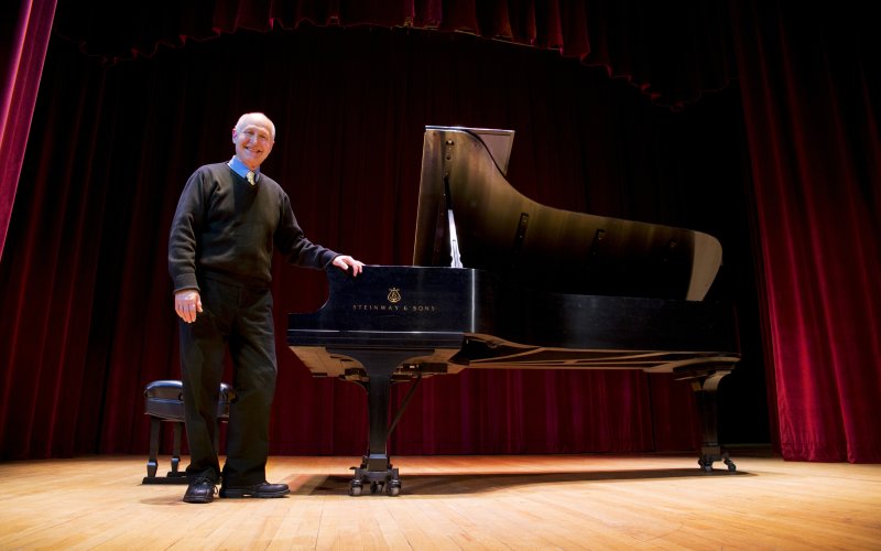 musician stands smiling by grand piano