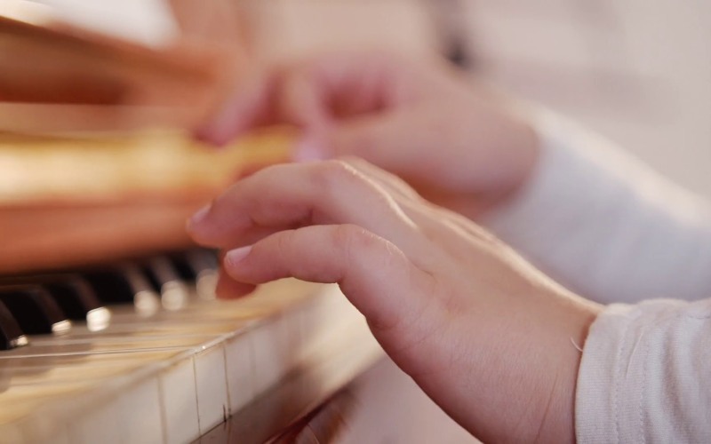 youngsters hands play on piano keyboard