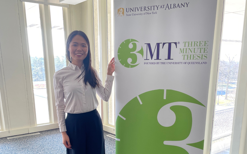 Charlotte stands next to a pull-up banner that has the 3MT logo on it.