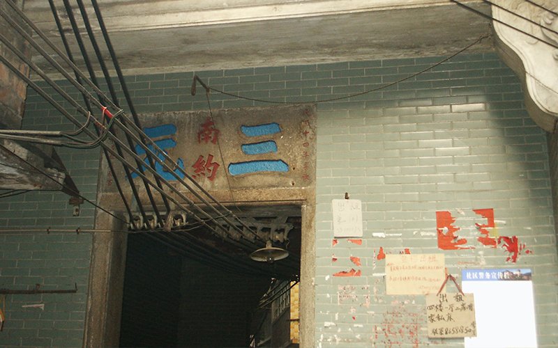 Handwritten signs hang on a faded and chipped hallway made of green tile, advertising rooms for rent in China