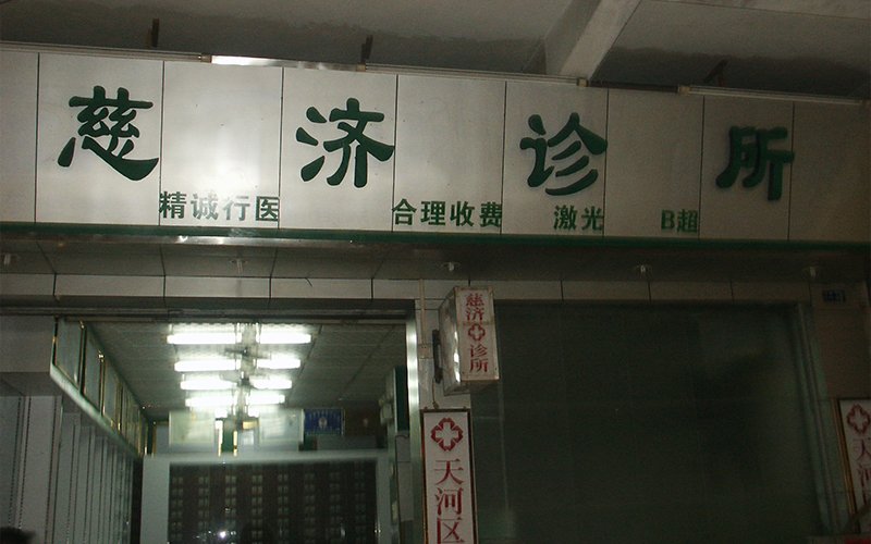 An entrance to Tzu Chi Clinic, with black Chinese lettering on metallic paneling overhead identifying the clinic and its services.