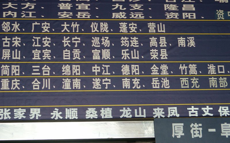 A black sign with white Chinese lettering displaying different destinations in China