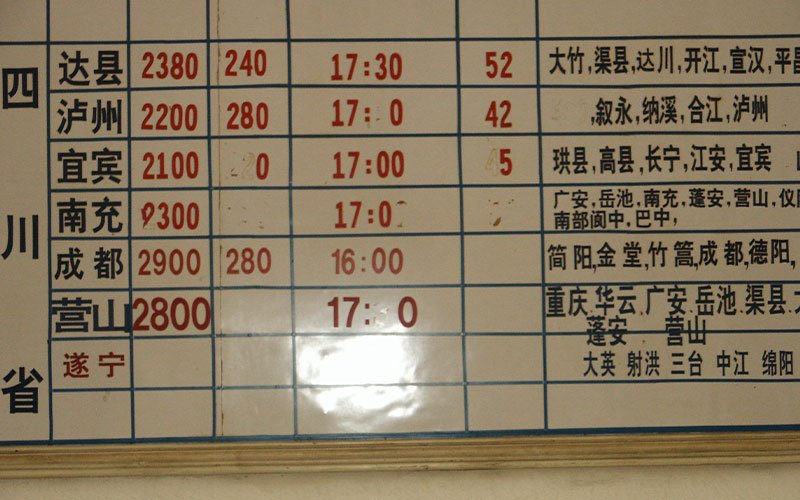 A transportation schedule on a white board, displaying times and locations in white and red Chinese lettering.