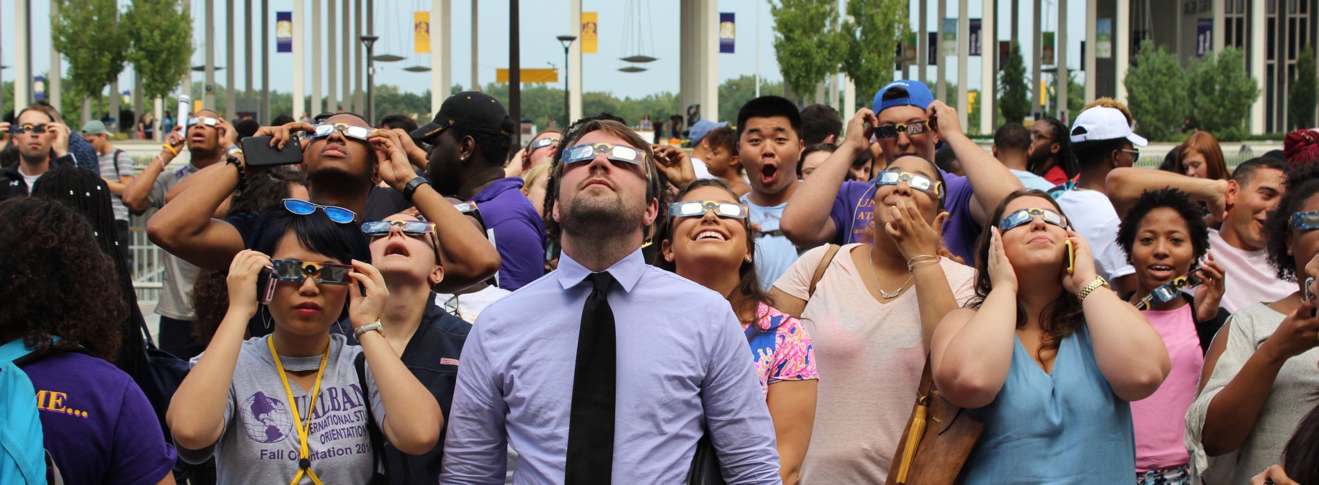 A crowd of people wearing eclipse glasses looks up at the sky ahead of the 2017 solar eclipse.