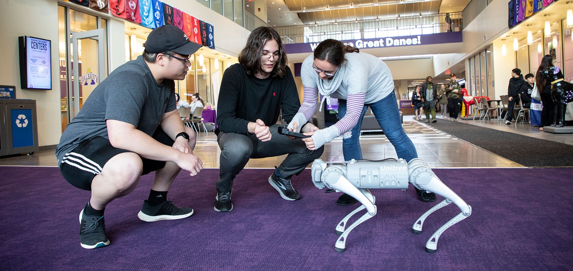 Three students working with a robot dog.
