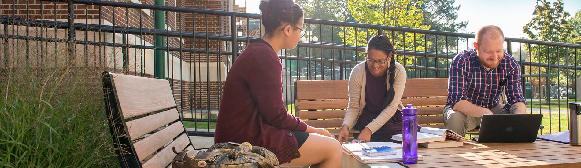 A group of three students studying in a UAlbany Downtown Campus courtyard.