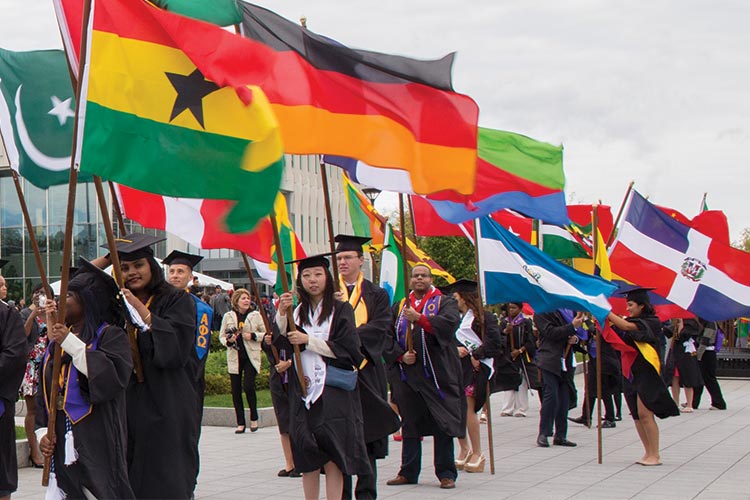 Students bear flags of their home countries at UAlbany commencement ceremony.