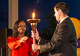 Passing the Torch: Outgoing Student Association President Arthur Rushforth passes the ceremonial University Torch to Junior Class Representative Minerve Delille at the Candle-lighting Ceremony during Commencement Weekend.