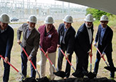 Photo of six men posing for groundbreaking event photo with shovels. 