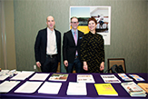 Photo of Edward Schwarzschild, Daniel Goodwin and Corinna Ripps Schaming standing behind their presentation table at the SOTUS Showcase.