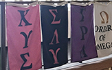 image shows four flags with greek letters designating different fraternities
