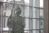 A statue of Minerva stands infront of a wall of windows