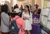 Studentslisten to a researcher at a campus research fair.
