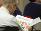 A man looks at icons on a sheet of paper, each representing one of 17 UN Glocal Goals for Sustainabilit