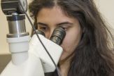 A woman looks through a microscope
