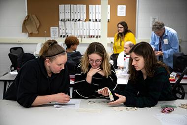 Three students work on costume design at a table