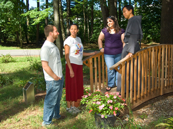From left, Hillel staffer David Hausler, UAlbany 2008 alumna Olivia Fagan, UAlbany senior Diana Landy, and Father Eric de la Pena gather at the bridge built in memory of Susan Sherman. 
