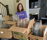 CEHC volunteer stands with boxes of face shields ready to be donated.