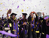 three graduates take a selfie as confetti falls behind them