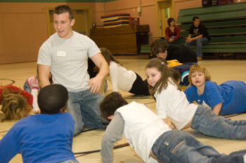 Children do push-ups as Greg Giambone tells them about the benefits of exercise.