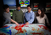 UAlbany atmospheric scientist Liming Zhou and student researchers point to a map which displays their research on the Congo rainforest.