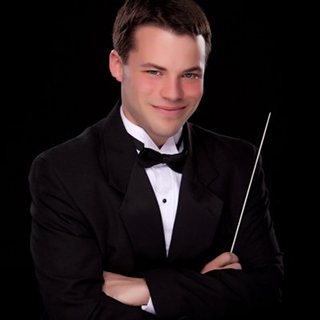 UAlbany choral director Michael Pfitzer, tuxedoed with baton in hand