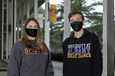 SST members Taylor Perre and David Skorodinsky stand on the Uptown Campus podium wearing masks.